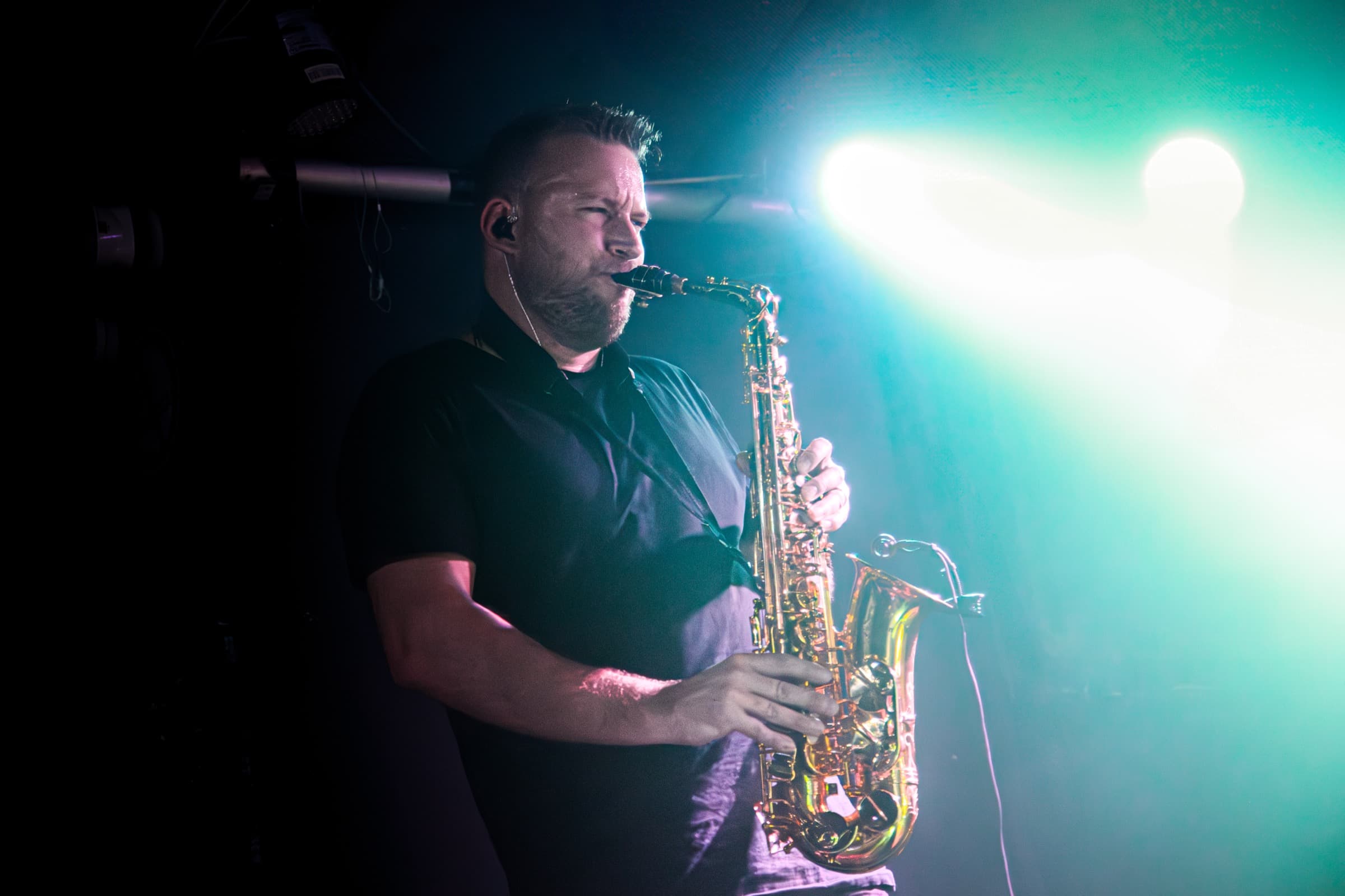 Tom Doesburg playing saxophone into a white stage flare.