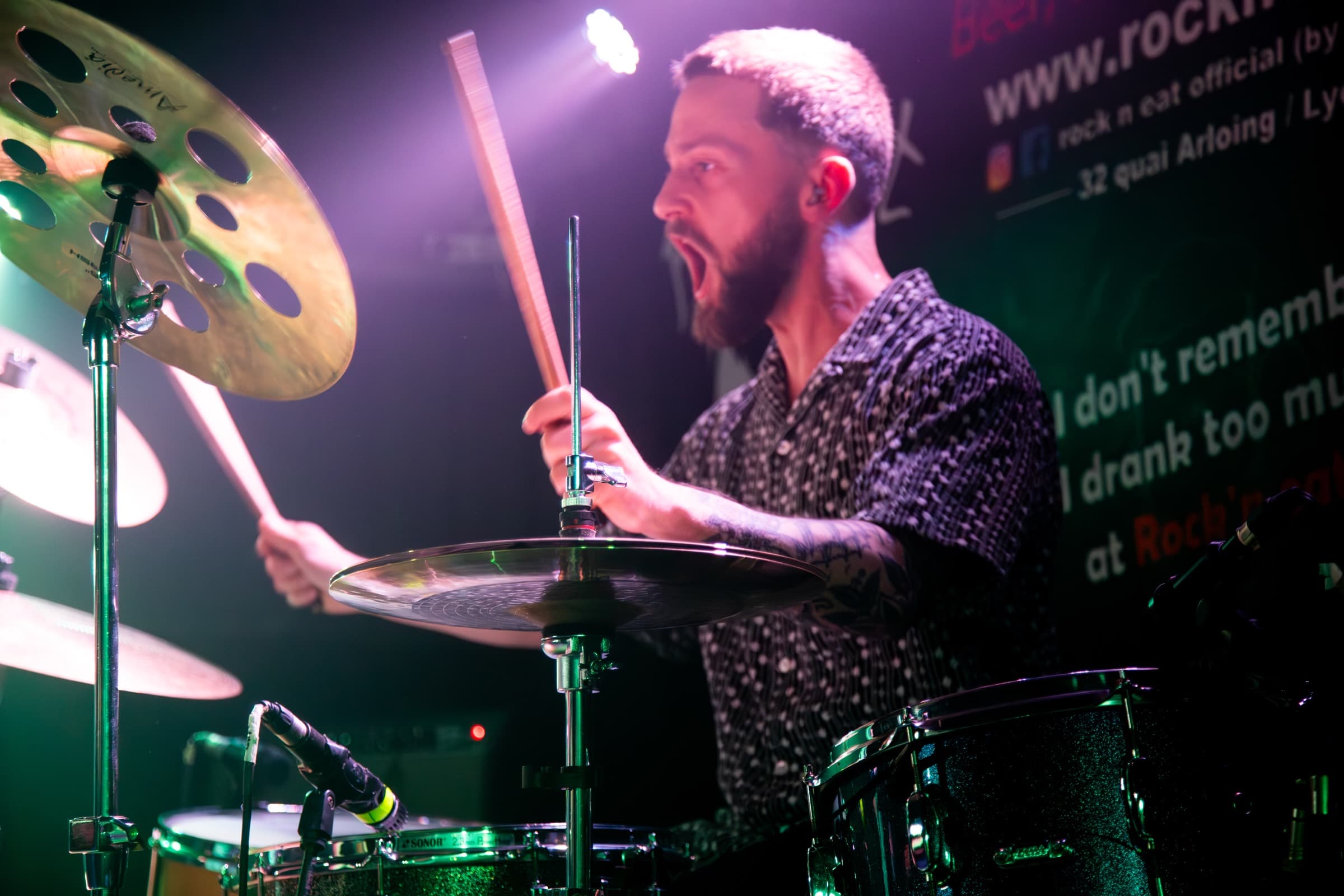Benoît Durbet striking drums through green and magenta stage light.